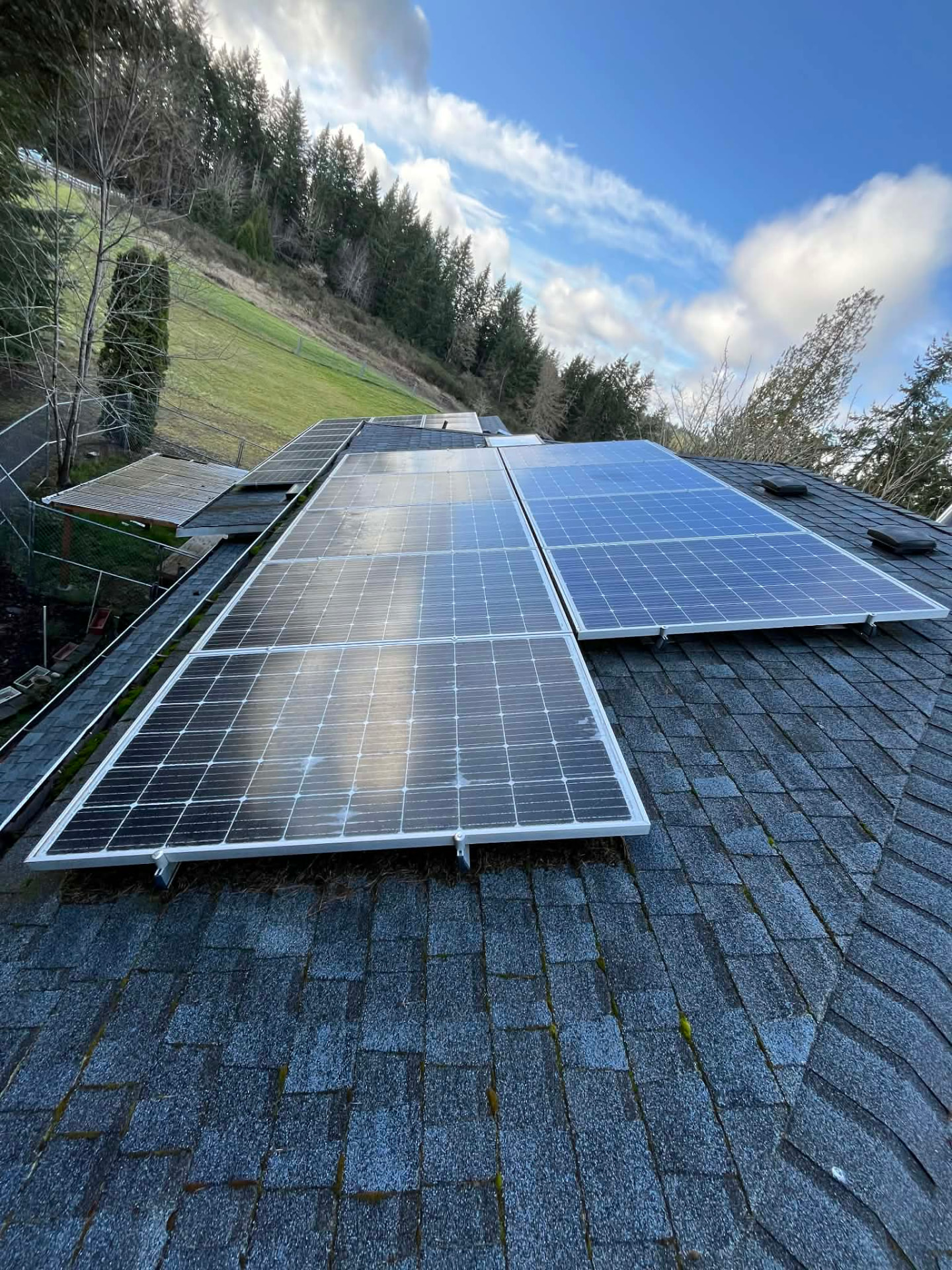 Clean solar panels on a shingle roof under a blue sky