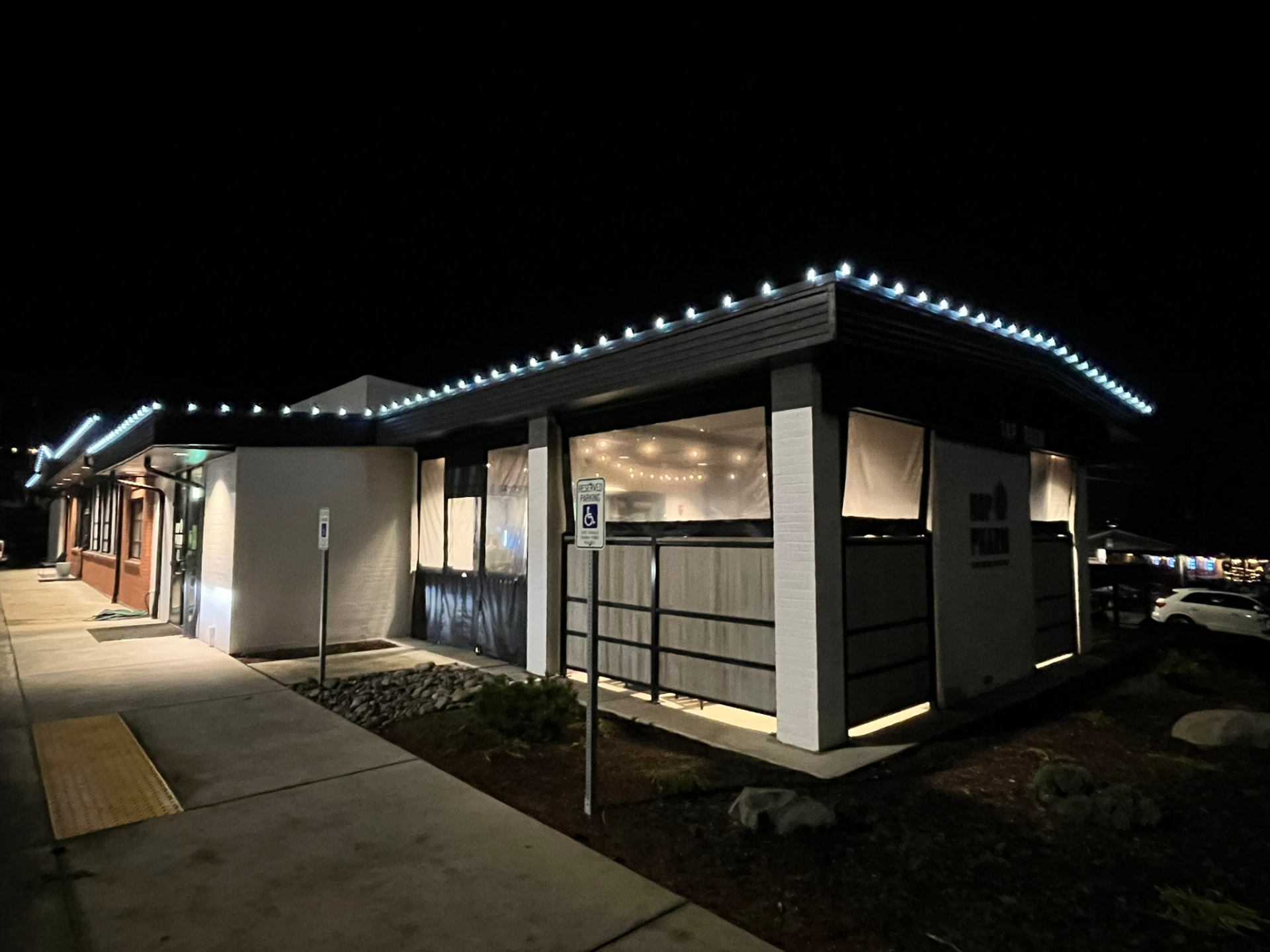 A local business building at night with blue holiday lights along the roof