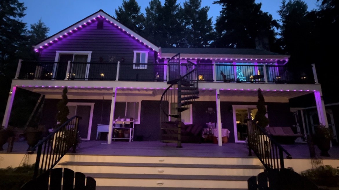 A house exterior at night lit with bright purple permanent lights