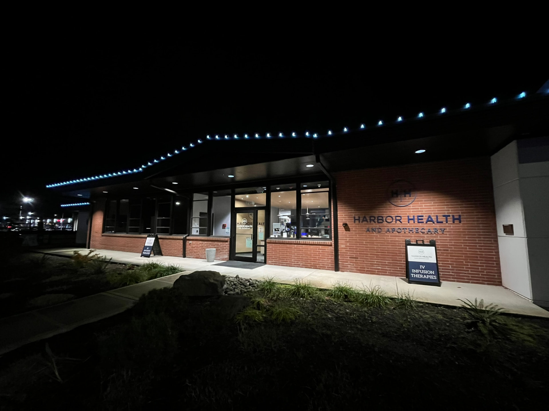 A commercial building at dusk with blue holiday lights strung along the roofline