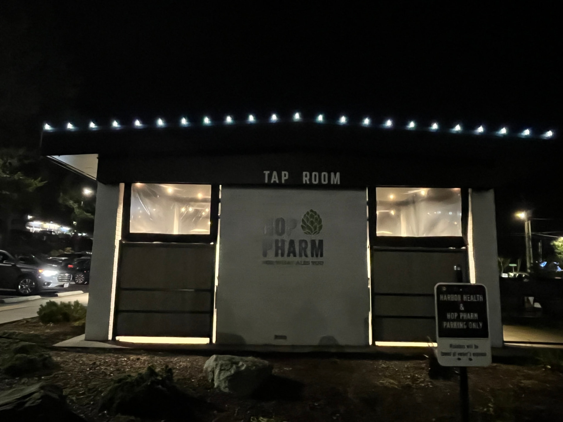 A tap room exterior at night with blue lights tracing the roofline