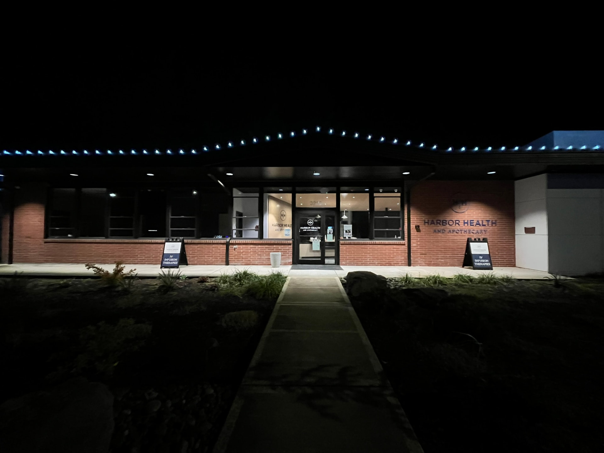 A harbour health building outlined in blue holiday lights at night