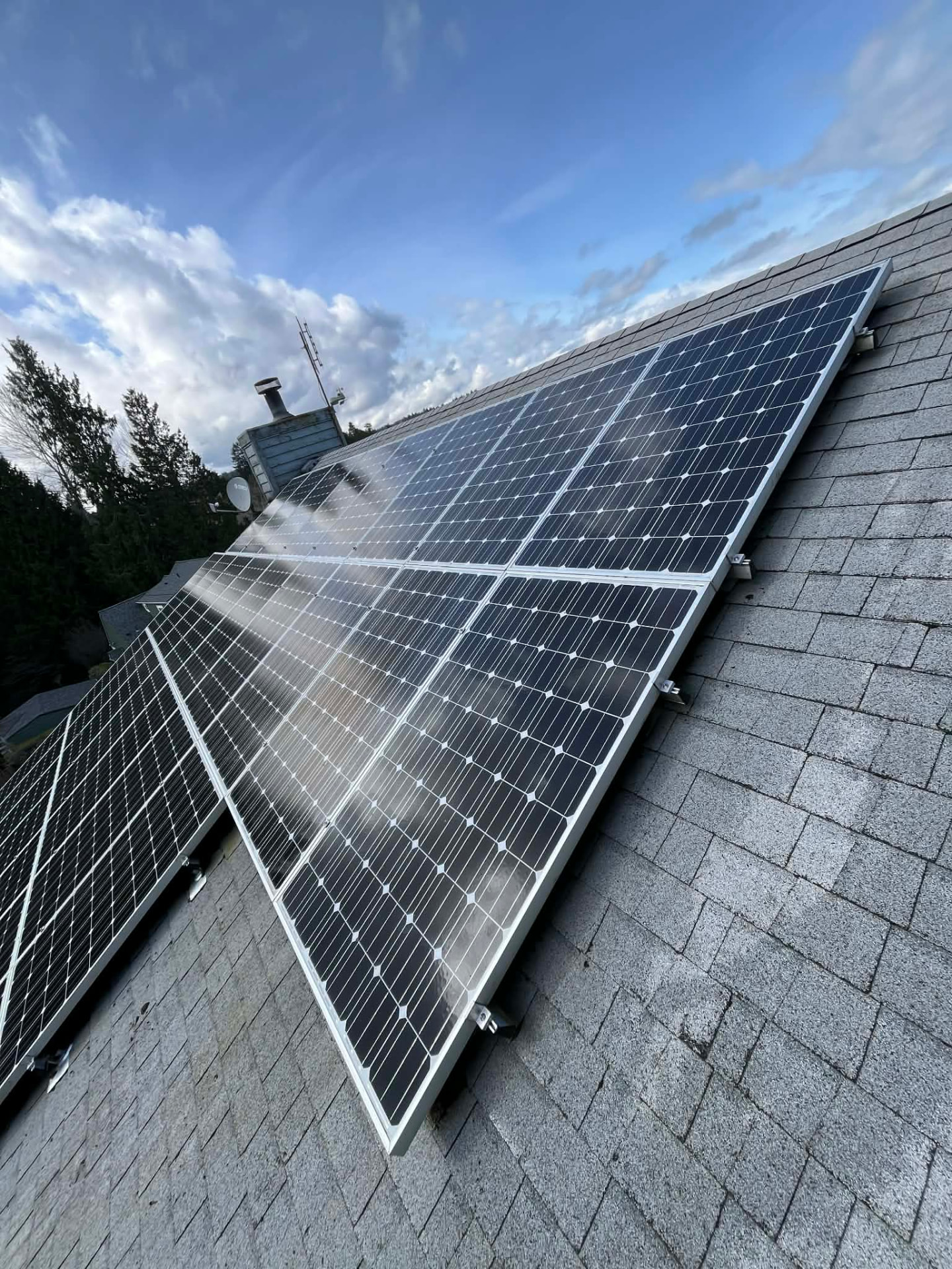 A bank of clean solar panels on a shingle roof